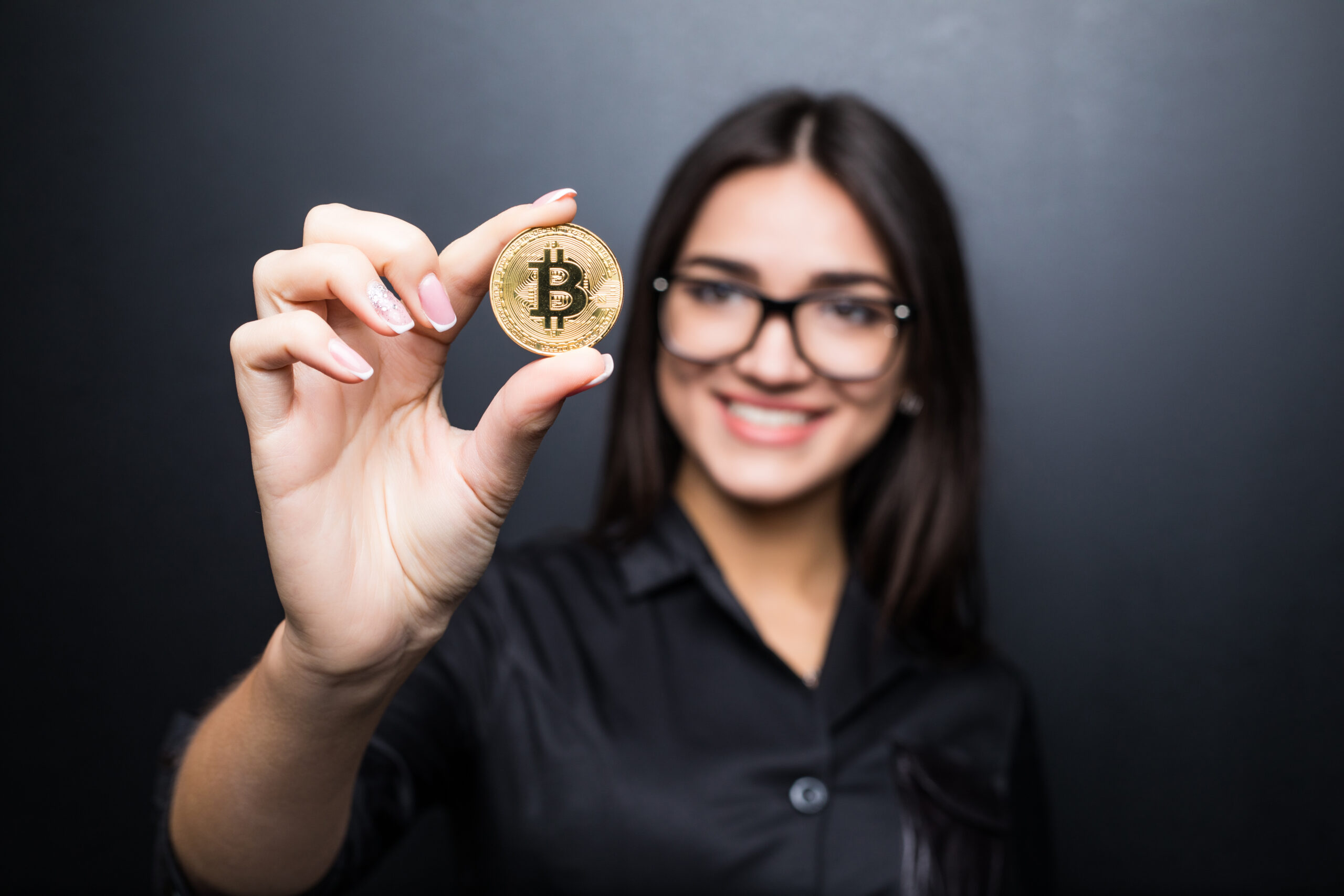 https://publiconline.com.br/wp-content/uploads/2022/06/young-successful-confident-woman-with-glasses-holds-a-gold-bitcoin-in-her-hand-isolated-on-black-wall-scaled.jpg